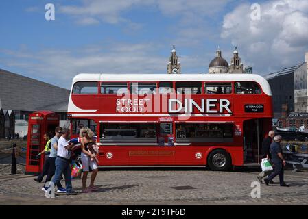Touristen laufen vorbei am Red Double-Decker Bus, der in Street Food Diner, Food Truck oder Restaurant an der Waterfront oder Pier Head Liverpool England UK umgewandelt wurde Stockfoto