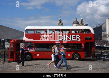 Touristen laufen vorbei am Red Double-Decker Bus, der in Street Food Diner, Food Truck oder Restaurant an der Waterfront oder Pier Head Liverpool England UK umgewandelt wurde Stockfoto