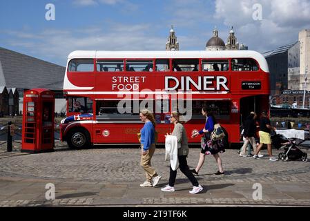 Touristen laufen vorbei am Red Double-Decker Bus, der in Street Food Diner, Food Truck oder Restaurant an der Waterfront oder Pier Head Liverpool England UK umgewandelt wurde Stockfoto