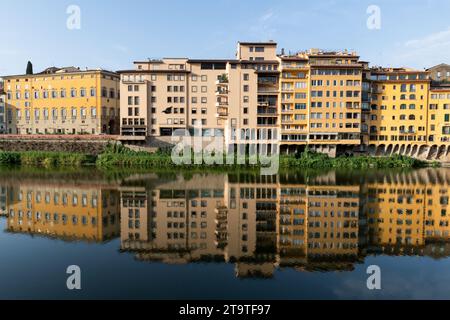 Farbenfrohe Gebäude spiegeln sich im stillen Wasser des Flusses Arno wider, der in der frühen Morgensonne durch Florenz, Toskana, Italien fließt. Stockfoto