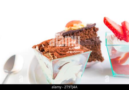 Köstliches Stück Schokoladenkuchen namens Tiramisu auf weiß in der Nähe von kleinen Kuchen Stockfoto