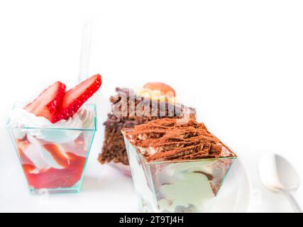 Köstliches Stück Schokoladenkuchen namens Tiramisu auf weiß in der Nähe von kleinen Kuchen Stockfoto