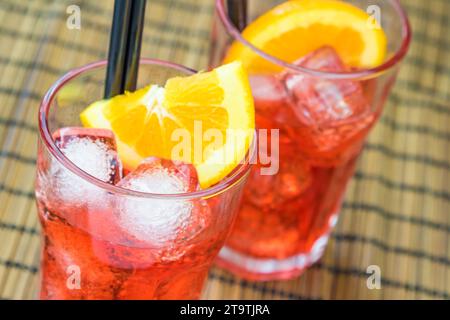 Zwei Gläser Spritz-aperol-Cocktail mit zwei Orangenscheiben und Eiswürfeln auf Holztisch Stockfoto