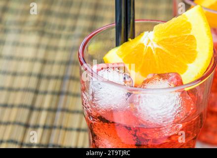 Aperitif-aperol-Cocktail mit Orangenscheiben und Eiswürfeln auf Holztisch Stockfoto