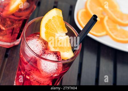 Nahaufnahme von Gläsern mit Spritz-Aperitif-aperol-Cocktail mit Orangenscheiben und Eiswürfeln auf Holztisch Stockfoto