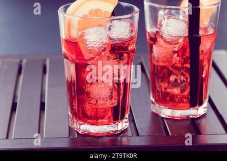 Spritzen Sie aperol-Cocktail mit zwei Orangenscheiben und Eiswürfeln auf Holztisch im Vintage-Stil Stockfoto