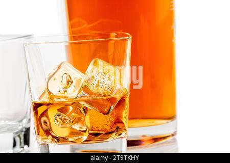 Zwei Gläser Whiskey in der Nähe der Flasche auf weißem Hintergrund mit Reflexion, Zeit der Entspannung mit Whisky Stockfoto