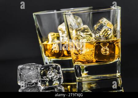 Zwei Gläser Whiskey in der Nähe von Eiswürfeln auf dunklem Hintergrund, Zeit der Entspannung mit Whisky Stockfoto