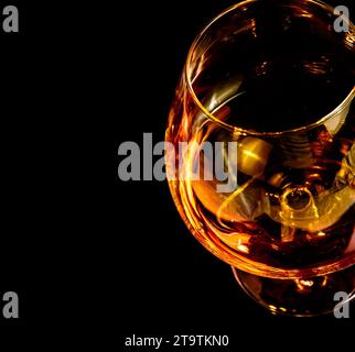 Schnitzel von Brandy in elegantem typischem Cognacglas auf schwarzem Hintergrund mit Platz für Text Stockfoto