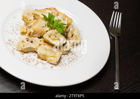 Detail des Gerichts italienischer Schwenkpasta mit Stachelpilzen und Sauce Bechamel mit Pfeffer in der Nähe der Gabel auf schwarzem Tisch Stockfoto