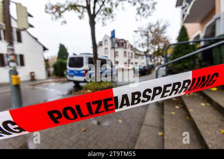 Freiburg, Deutschland. November 2023. Ein Band mit der Aufschrift „Police Cordon“ hängt über einer Straße, während ein Polizeifahrzeug im Hintergrund zu sehen ist. Nach der Entdeckung einer 105-mm-Flugabwehrgranate aus dem Zweiten Weltkrieg während der Bauarbeiten wurden rund 200 Menschen vorsorglich in Sicherheit gebracht. Aufgrund des Zustands der Munition wurde sie an Ort und Stelle explodiert. Quelle: Philipp von Ditfurth/dpa/Alamy Live News Stockfoto