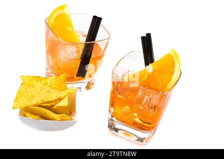 Oberer Blick auf zwei Gläser Spritz-aperol-Cocktail mit Orangenscheiben und Eiswürfeln in der Nähe von Tacos-Chips auf weißem Tischhintergrund Stockfoto