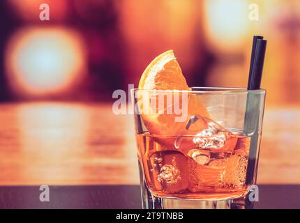 Ein Glas Spritz-aperol-Cocktail mit Orangenscheiben und Eiswürfeln auf dem Bartisch, Vintage-Atmosphäre im Hintergrund, Lounge-Bar-Konzept Stockfoto