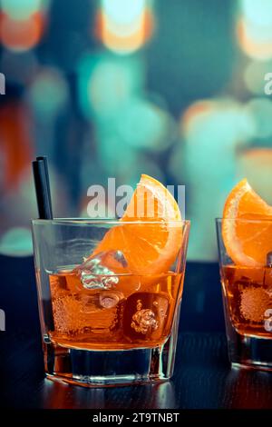 aperol-Cocktail mit Orangenscheiben und Eiswürfeln auf dem Bartisch, Pop-Atmosphäre im Hintergrund, Lounge-Bar-Konzept Stockfoto