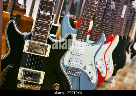 Eine Sammlung von Gitarren mit elektrischer Karosserie, die in einer Reihe hängen Stockfoto