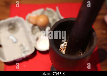 Allgemeine Sicht auf einen Holzmörtel und Pissel mit zerquetschten Eierschalen. Stockfoto