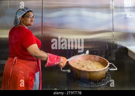 Schwarze Frau rührt kochenden Topf, während sie Pralinen im French Quarter von New Orleans, Louisiana, herstellt Stockfoto