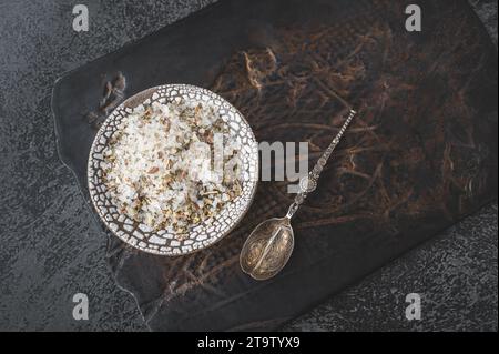 Mischung aus trockenen Gewürzen, Kräutern und Salz in einer handgefertigten Kraftplatte auf einem Tonschneidebrett. Adygeasalz. Draufsicht. Kopierbereich. Stockfoto