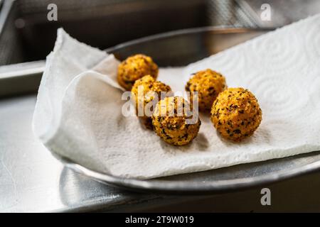 Luxuriöse Vorspeise mit gebratenen Kartoffelbällchen mit Kräutern in der Küche eines Restaurants. Lebensmittelfotografie Konzeptbild Stockfoto