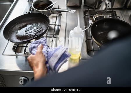 Koch-Schaukeln ölen Sie eine beheizte Skillet im Restaurant. Bild des Kochkonzepts des Luxushotels. Stockfoto