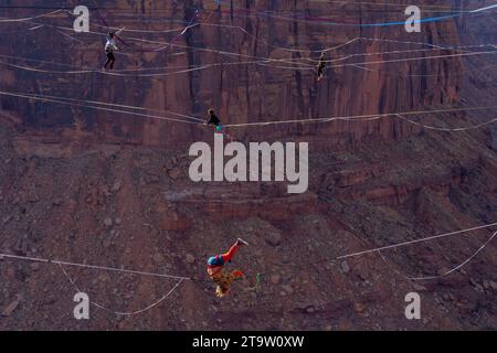 Vier Personen auf Highlines beim GGBY World Highline Festival 500 Fuß über dem Mineral Canyon in der Nähe von Moab, Utah. Ein Freestyler vorne macht einen Schultersteg Stockfoto