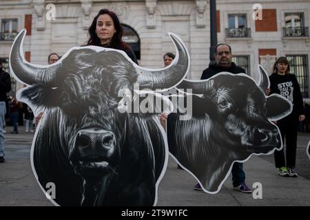 Madrid, Spanien. November 2023. Ein Anti-Stierkampf-Aktivist steht bei einem Protest vor dem Präsidentengebäude der Gemeinschaft Madrid unter den Papptierköpfen. Aktivisten des Internationalen Anti-Stierkampf-Netzwerks mit riesigen Stier- und Pferdeköpfen führen im Zentrum von Madrid eine Protestaktion für die Abschaffung des Stierkampfes durch. Quelle: SOPA Images Limited/Alamy Live News Stockfoto