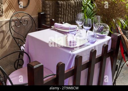 Lila Restauranttisch bereit für den Empfang von Gästen. Dorf Cortona, Italien. Stockfoto