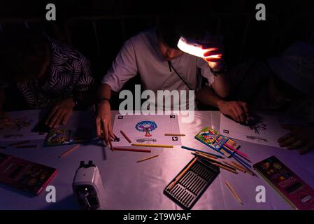 Bangkok, Thailand. November 2023. Ein Mann sah einen „Krathong“ während des Loy Krathong Festivals am Khlong Ong Ang Kanal in Bangkok malen. Der virtuelle Loy Krathong mit Projektionskartierung fand am Khong Ong Ang Kanal in Bangkok statt. Diese Idee zielt darauf ab, Abfall beim jährlichen Loy Krathong Festival zu reduzieren. Quelle: SOPA Images Limited/Alamy Live News Stockfoto