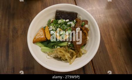 Rindfleischnudeln Chilisauce serviert in einer Schüssel auf dem Tisch mit Blick auf taiwanesische Speisen. Suppe Rindernudeln in einer Schüssel auf Holztisch. Chinesische taiwanesische Küche Stockfoto