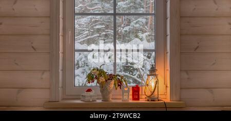 Weihnachtslaterne, Weihnachtskaktus, Geschenk, Kerzen am Fenster des Holzhauses, Wintergarten Stockfoto