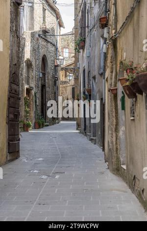 Stadtbild mit alten Tuffhäusern auf einer Bergstraße in einem historischen Dorf auf einem Hügel, aufgenommen im hellen frühen Herbstlicht in Pitigliano, Toskana, Italien Stockfoto