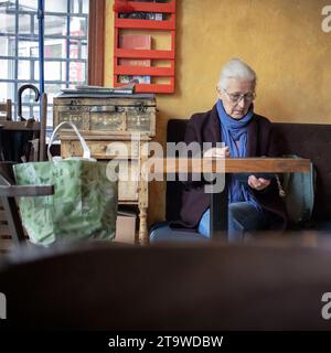 Belgrad, Serbien, 19. November 2023: Eine grauhaarige Frau sitzt in einem Café und wartet auf ihre Bestellung Stockfoto