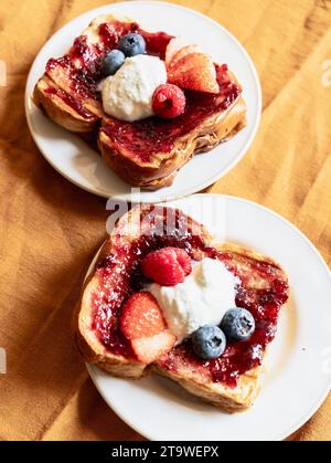 Nahaufnahme von zwei Brioche-Toasts mit Marmelade und Beeren plus Blaubeeren, vertikales Foto Stockfoto