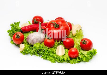 Tomaten, Pfeffer, Knoblauch, Salatblätter. Veganes Diätfutter, kreative Zusammensetzung isoliert auf weiß Stockfoto