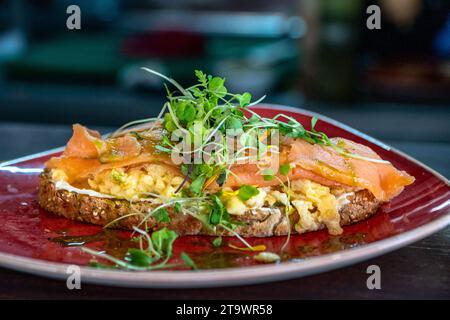 Geröstetes Brot, Frischkäse, belegt mit Rührei und Räucherlachs. Stockfoto