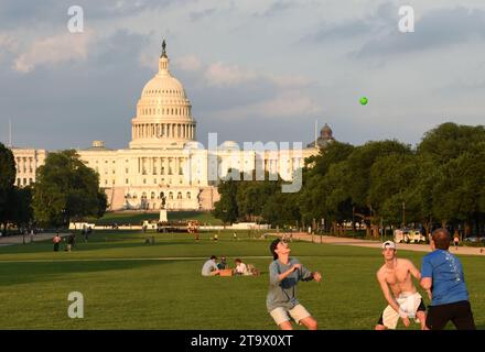 Washington, DC - 2. Juni 2018: Die Leute ruhen sich aus und spielen den Ball in der National Mall mit dem United States Capitol im Hintergrund. Stockfoto
