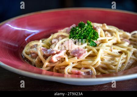 Eine frisch zubereitete Spaghetti Carbonara, serviert in einer roten Schüssel Stockfoto
