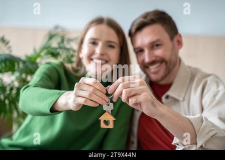 Fröhlich lächelndes Paar, das Schlüssel für eine neue Wohnung zeigt, ein Haus, das stolz darauf ist, ein eigenes Grundstück zu kaufen Stockfoto