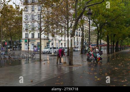 Paris, Frankreich, 2023. Ein Obdachloser sammelt an einem dunklen regnerischen Tag auf dem Boulevard Richard Lenoir in der Nähe des Place de la Bastille tote Blätter Stockfoto