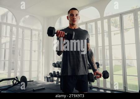 Junger tätowierter multirassischer Mann im Sportswear-Krafttraining im Fitnessstudio Stockfoto