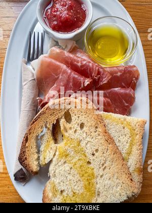 Serrano-Schinken-Toast mit Tomaten und Olivenöl auf dem Restauranttisch Stockfoto