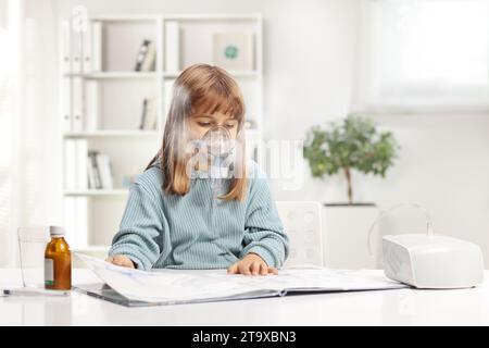 Ein kleines Mädchen liest ein Buch und benutzt zu Hause einen Vernebler mit Dampfnebel Stockfoto