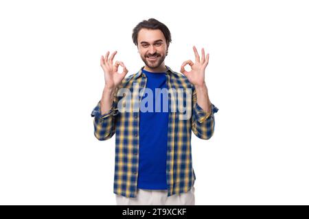 Ein junger kaukasischer brutaler Mann mit einem unrasierten Gesicht in einem blauen karierten Hemd zeigt, dass alles in Ordnung ist Stockfoto