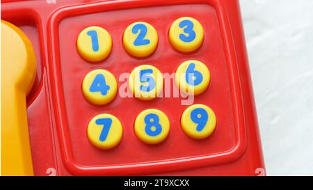 Einfaches farbenfrohes kleines Telefon Festnetztelefon Spielzeug mit kleinen Zifferntasten, Tastatur Details, niemand. Lernen von Zahlen, Mathematik, Spielzeug für Kinder und Stockfoto