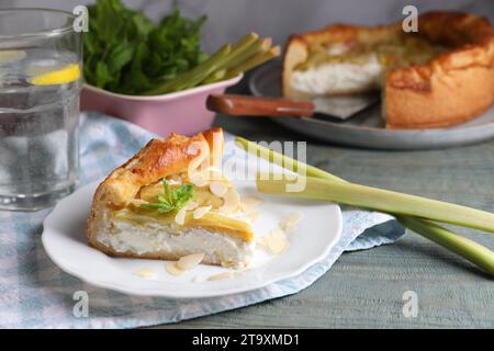 Frisch gebackener Rhabarberkuchen mit Frischkäse, Stängeln und Mandelflocken auf grauem Holztisch Stockfoto