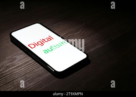 Smartphone mit Phrase Digital Autism auf Holztisch, Platz für Text. Suchtverhalten Stockfoto