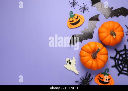 Flache Lay-Komposition mit Fledermäusen, Kürbissen, Geistern und Spinnen auf violettem Hintergrund, Platz für Text. Halloween-Feier Stockfoto