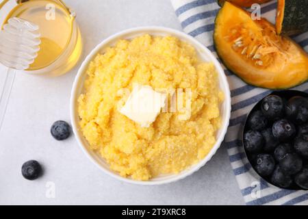 Leckeres Maismehl mit Butter in der Schüssel und Produkten auf hellgrauem Tisch, flach gelegt Stockfoto