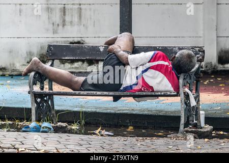 Ein armer Mann schläft auf einer Parkbank Stockfoto
