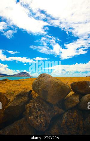 Türkisfarbenes Wasser sprudelt und plätschert an einem felsigen Ufer. Über dem Meer erstreckt sich ein riesiger blauer Himmel bis zum Horizont. Stockfoto
